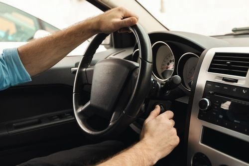 Closeup of man putting car key to the keyhole, starting the car or stopping engine