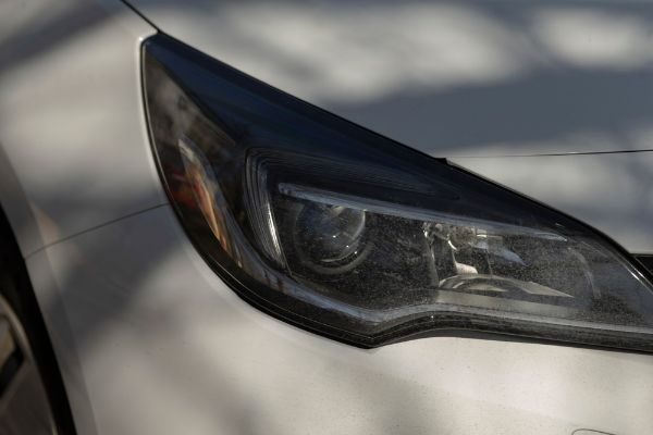A closeup view of a cars headlight, shining brightly on a dimly lit street