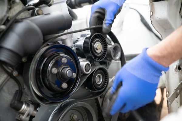 Mechanic Working on vehicle Timing Belt Replacement in Automotive Shop